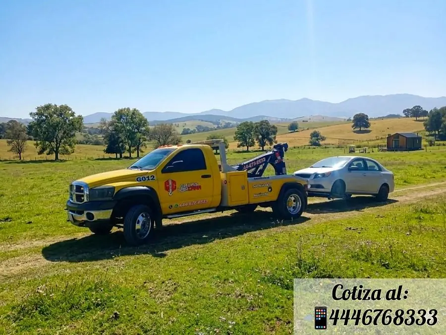 Grúa HERCARR trasladando un vehículo en camino foráneo